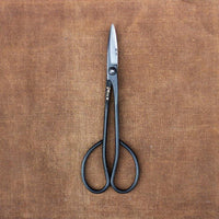 Long handled metal scissors with engraved Japanese characters on brown cloth