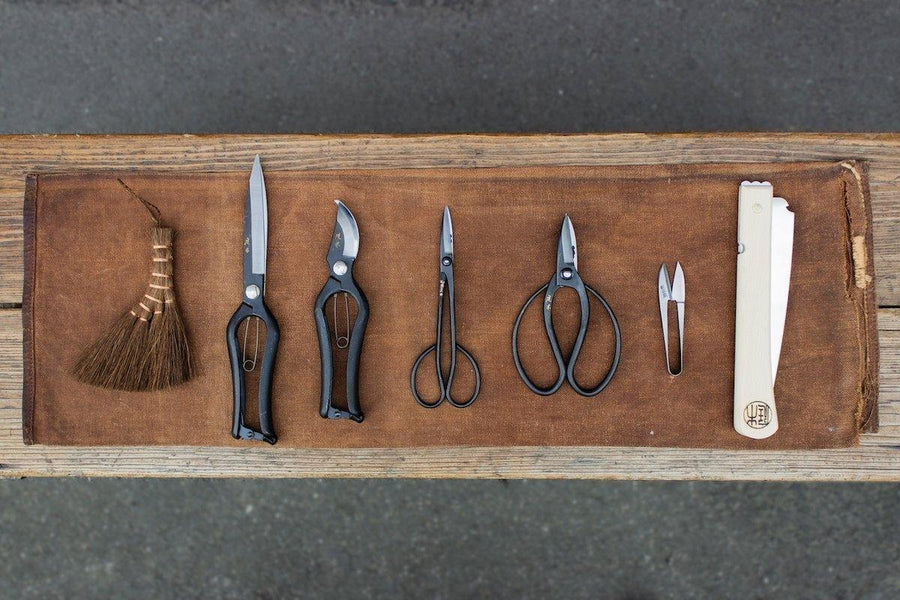 Assorted gardening tools on brown fabric on wooden bench