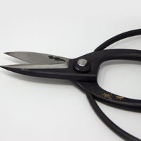 Close up short scissor blades with black metal handle and engraved Japanese characters on grey background