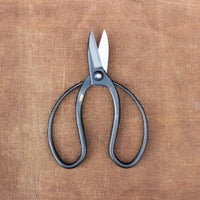 Round handled black metal scissors on brown cloth