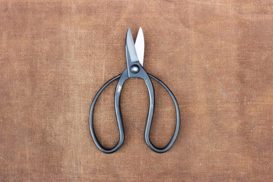Round handled black metal scissors on brown cloth
