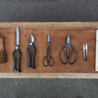 Assorted gardening tools on brown fabric on wooden bench