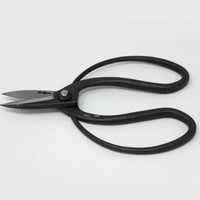 Large handled black metal scissors with engraved Japanese characters on grey background