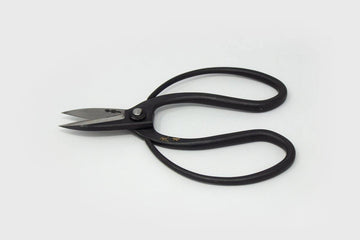 Large handled black metal scissors with engraved Japanese characters on grey background