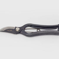 Black metal secateurs with engraved Japanese characters on grey background