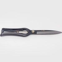 Black metal shears with engraved Japanese characters and long blades on grey background