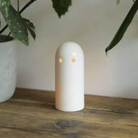 Glowing white ceramic candle holder on wooden table