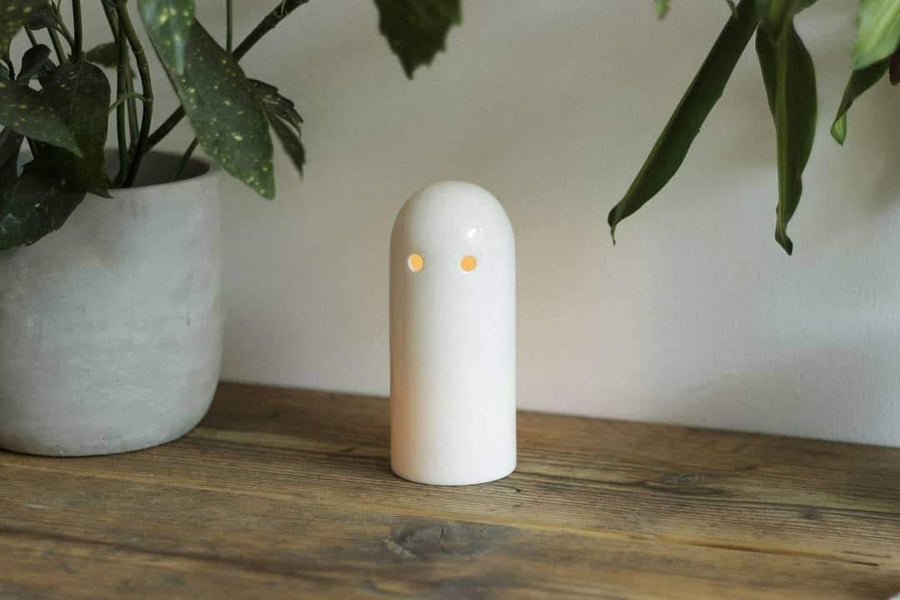 Glowing white ceramic candle holder on wooden table