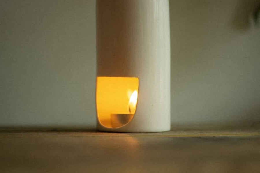 Lit candle inside ceramic candle holder on wooden table